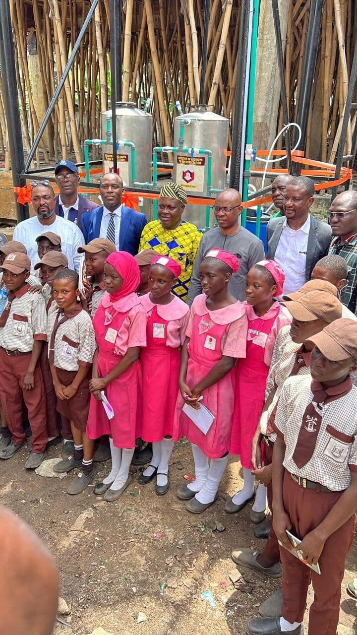 Schoolgirls and visiting dignitaries gathered in front of the Eko Boys To Men water purification tanks donated to Boys Academy